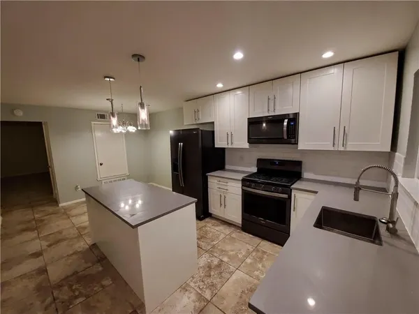 a kitchen with stainless steel appliances granite countertop a sink a stove a refrigerator and a microwave