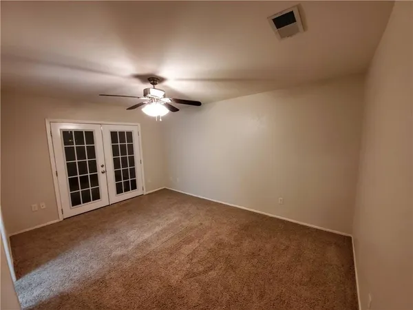 an empty room with windows and ceiling fan
