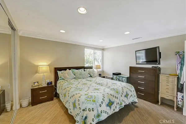 a bedroom with a bed and a flat tv screen on dresser