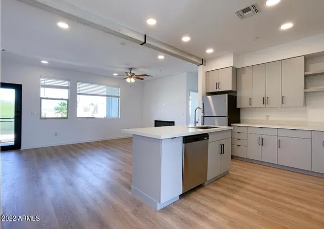 a kitchen with stainless steel appliances granite countertop a sink cabinets and wooden floor