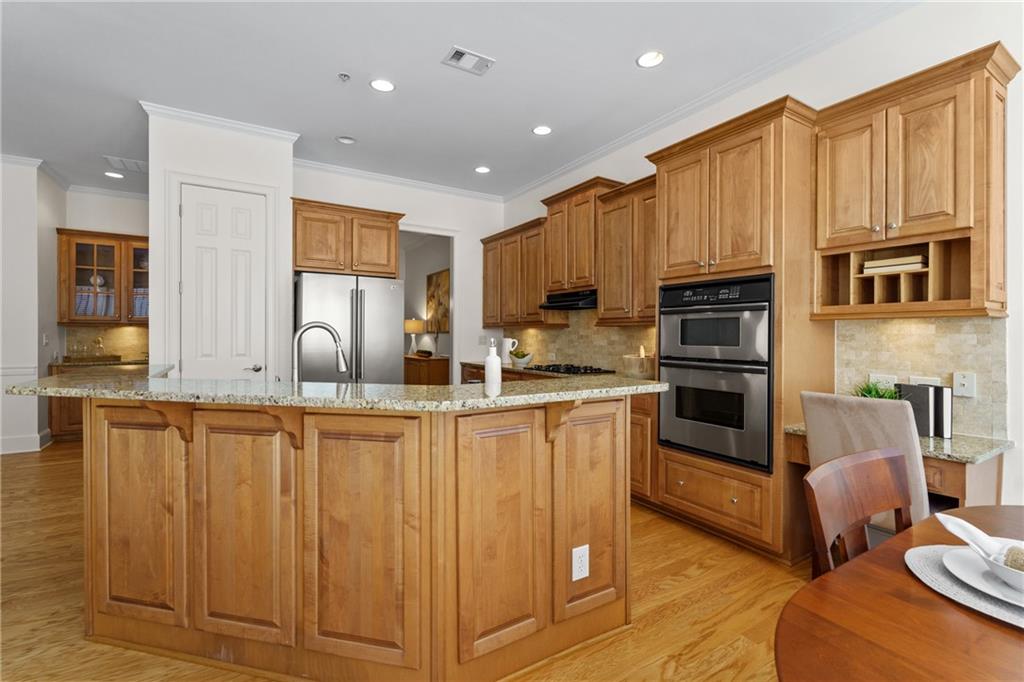 11945 Dancliff Trace Alpharetta, GA 30009 - Photo 12 of 48 a kitchen with stainless steel appliances granite countertop a refrigerator a stove top oven and a sink with wooden floors