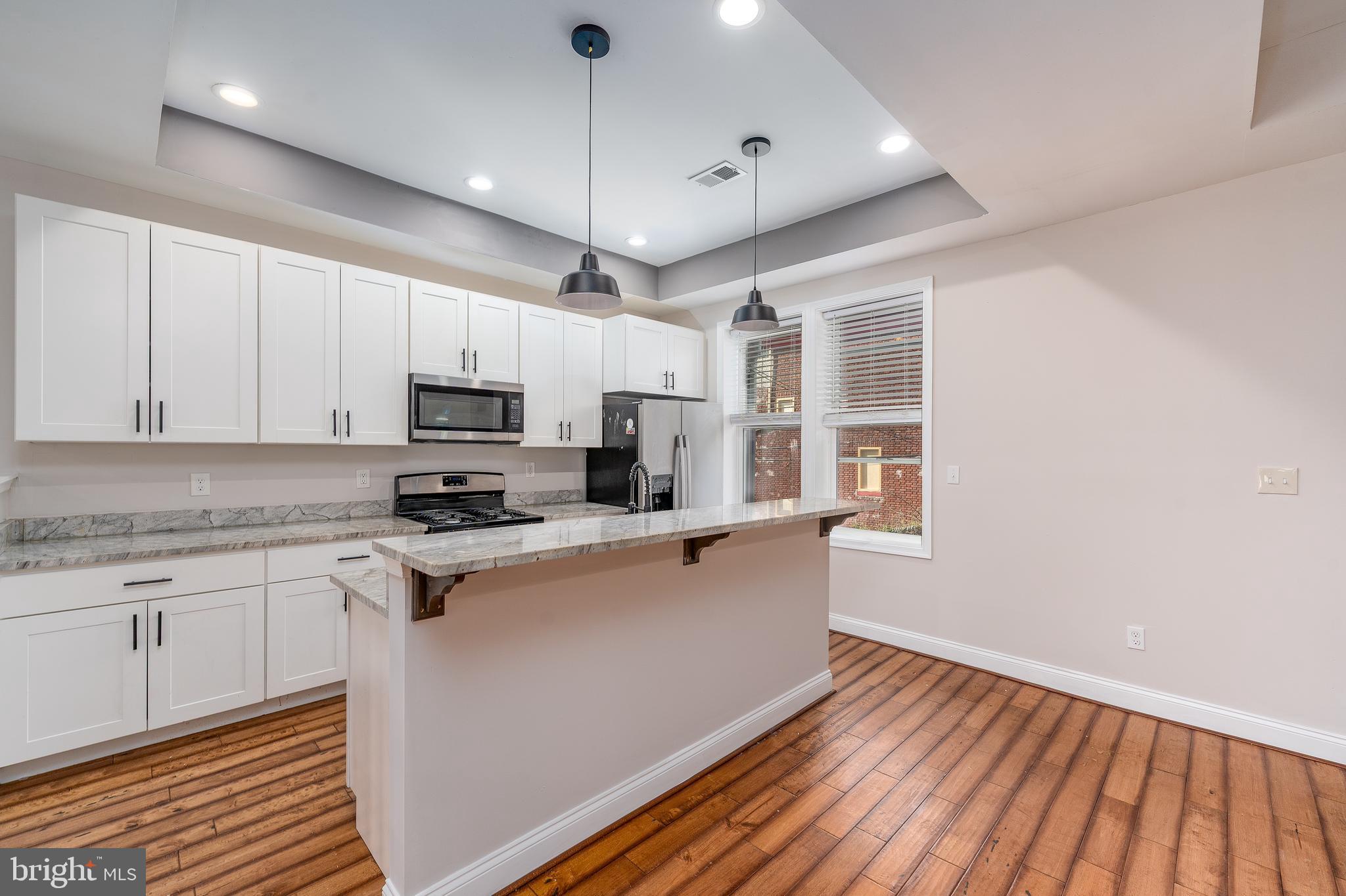 3506 Reisterstown Road Baltimore, MD 21215 - Photo 12 of 32 a kitchen with stainless steel appliances granite countertop a sink dishwasher a refrigerator white cabinets and wooden floor