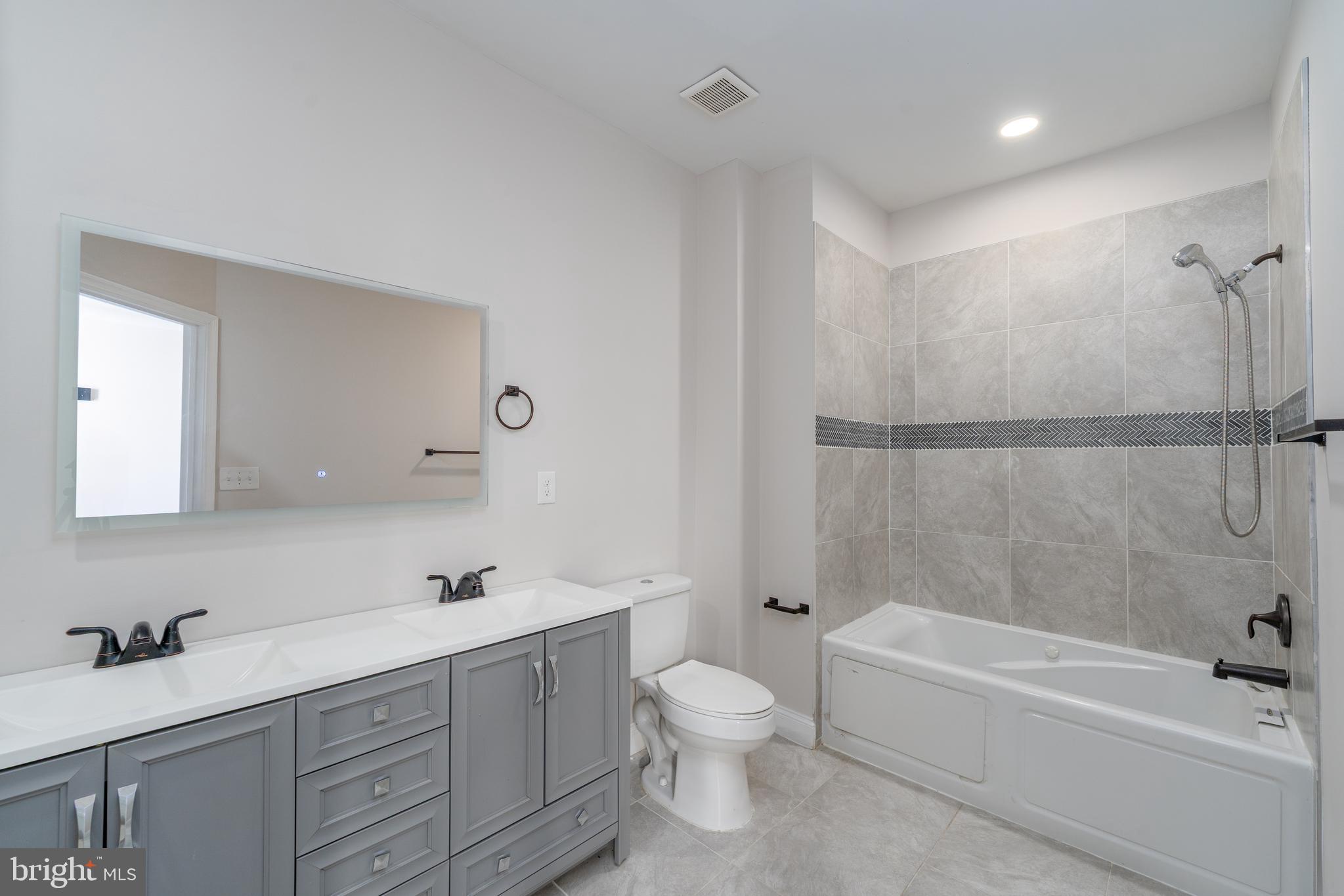 3506 Reisterstown Road Baltimore, MD 21215 - Photo 17 of 32 a bathroom with a bathtub shower sink vanity mirror and toilet
