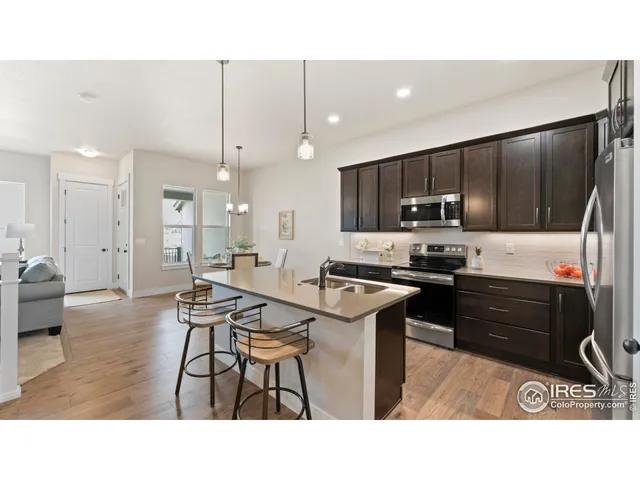 a kitchen with kitchen island a stove a refrigerator a sink dishwasher with a dining table and chairs