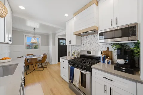 a kitchen with stainless steel appliances granite countertop a stove a sink dishwasher and cabinets with wooden floor