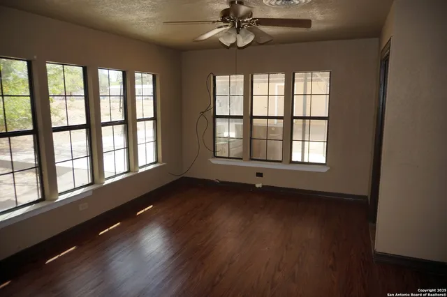 an empty room with wooden floor and windows