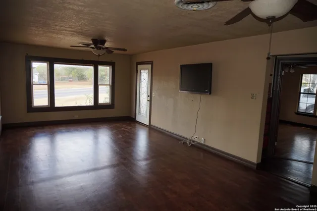an empty room with wooden floor and windows
