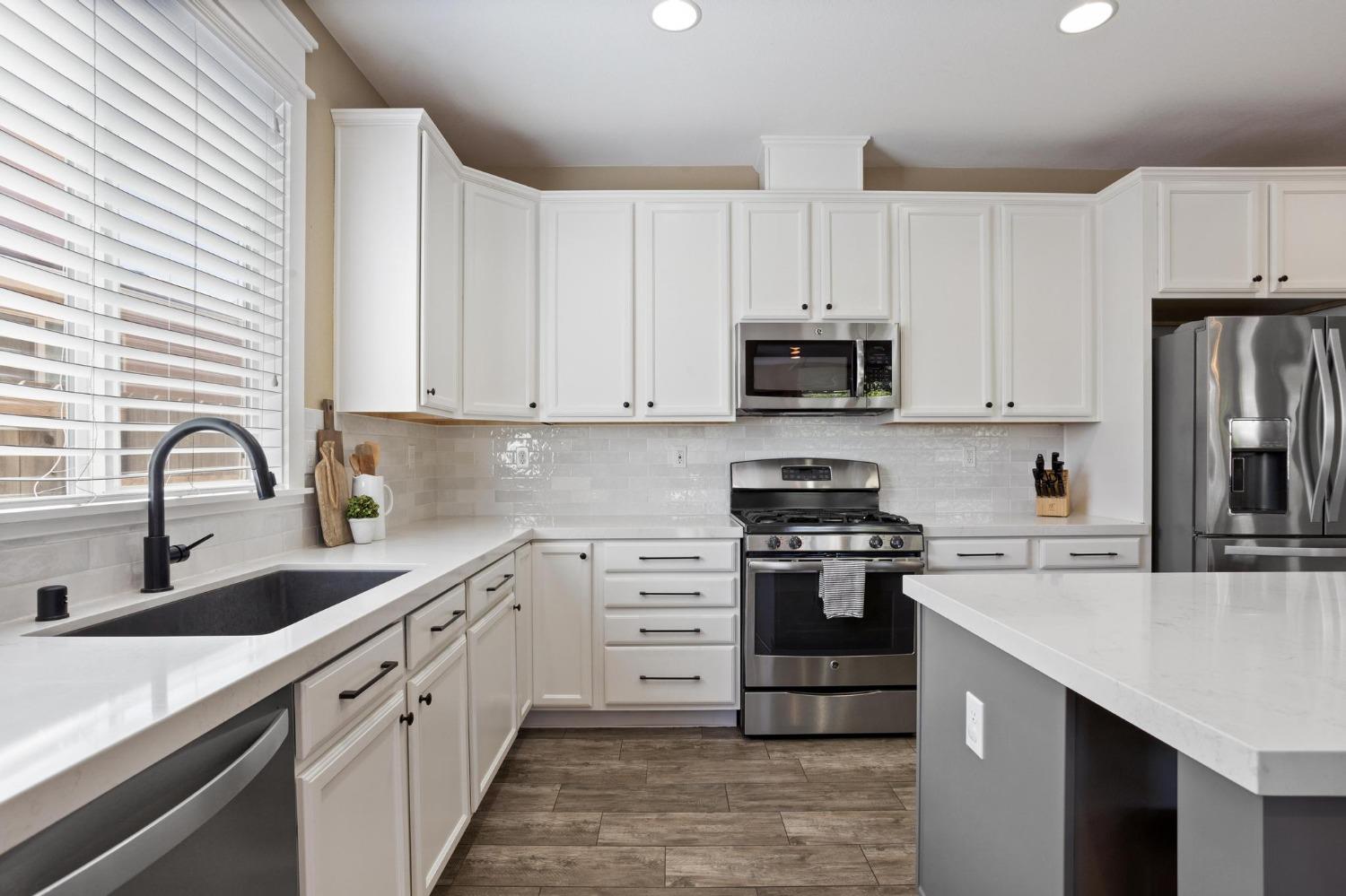 a kitchen with stainless steel appliances granite countertop white cabinets a stove a sink and dishwasher