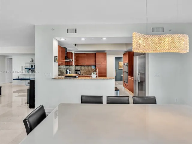 a kitchen with stainless steel appliances a table and chairs in it