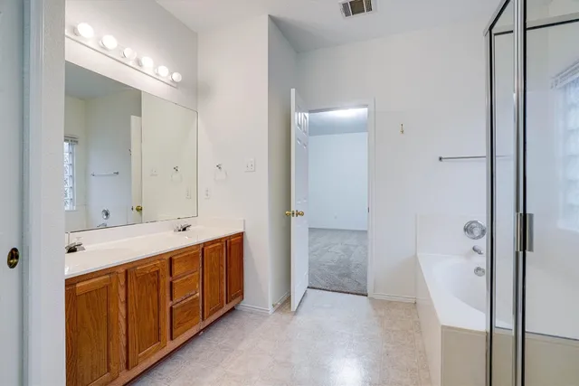 a spacious bathroom with a double vanity sink a mirror and a shower