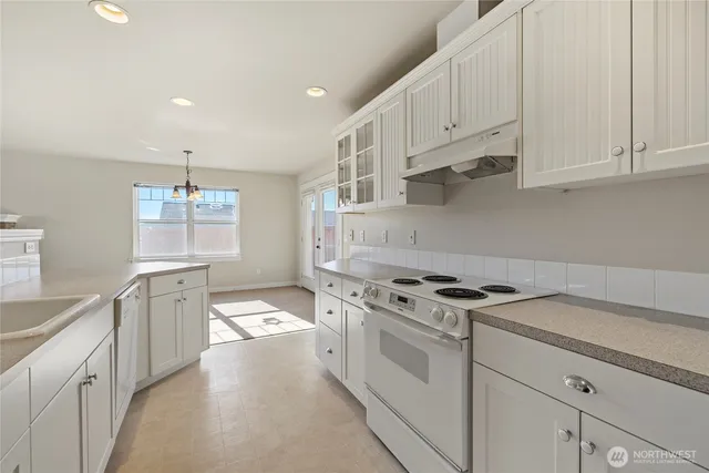 a kitchen with granite countertop white cabinets and white appliances