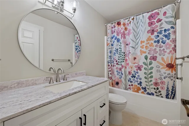a bathroom with a granite countertop sink mirror vanity and toilet