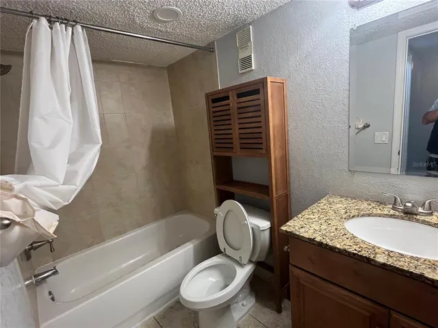 a bathroom with a granite countertop toilet sink and mirror