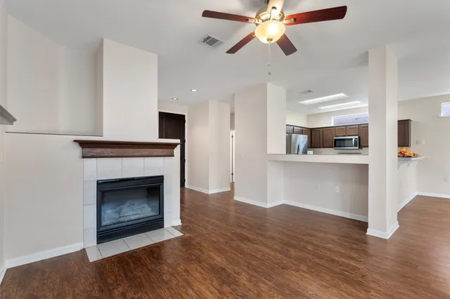 a view of an empty room with kitchen and fireplace