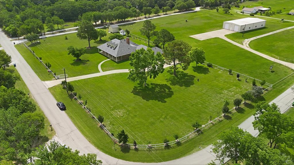 6955 Hawk Road Flower Mound, TX 75022 - Photo 34 of 40 Expansive property featuring a single-story residence with a covered porch, a separate large outbuilding, a circular drive, mature trees, and a perimeter fence