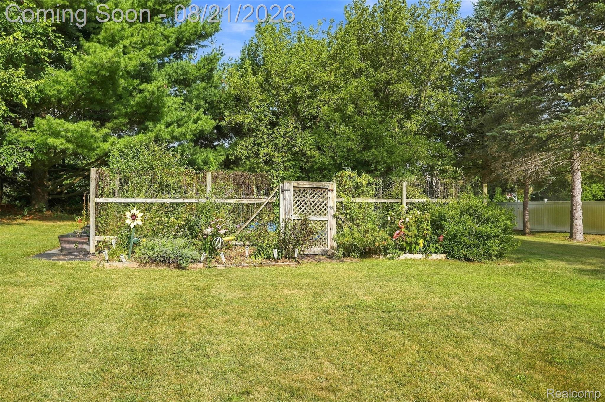 6060 Ford Road Commerce Township, MI 48382 - Photo 43 of 58 Expansive green lawn with mature trees and a fenced garden area featuring a lattice gate