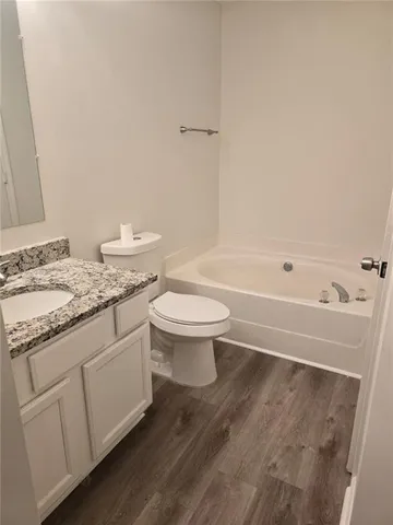 a bathroom with a granite countertop sink a toilet and a bathtub