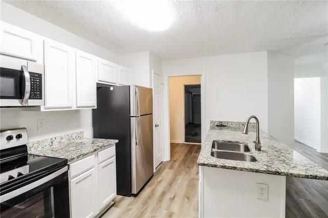a kitchen with granite countertop a sink stove and refrigerator