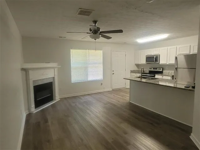 a kitchen with granite countertop a refrigerator oven a sink dishwasher and a stove top oven with wooden floor