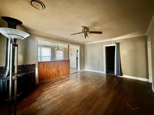 a view of an empty room with a window and wooden floor