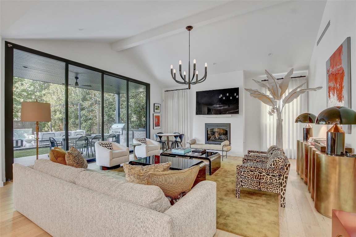 2006 Ford Street Austin, TX 78704 - Photo 4 of 40 Living room with beamed ceiling, light wood finished floors, a glass covered fireplace, a chandelier, and high vaulted ceiling