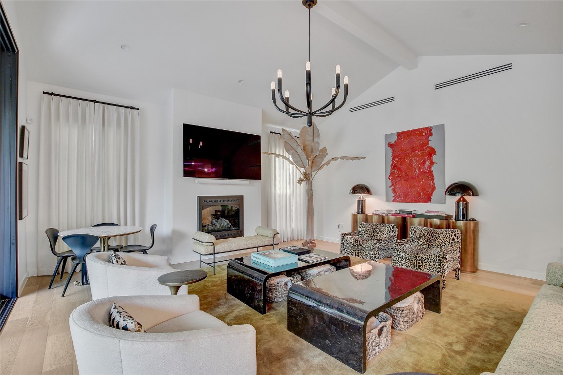 2006 Ford Street Austin, TX 78704 - Photo 5 of 40 Living room with wood finished floors, beam ceiling, a chandelier, high vaulted ceiling, and a glass covered fireplace