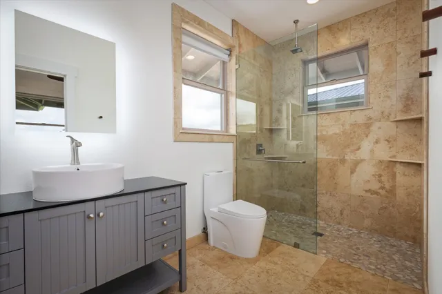 a bathroom with a granite countertop sink a toilet a mirror and shower