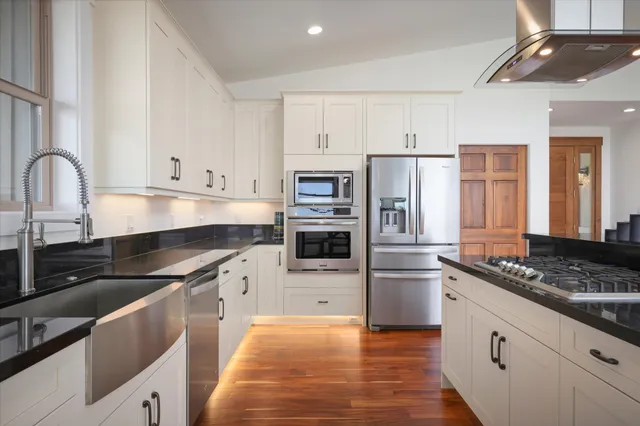 a kitchen with granite countertop a refrigerator and a stove top oven