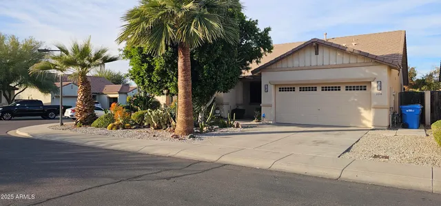 a view of a house with small yard plants and palm trees