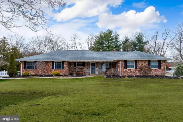a view of a big house with a big yard and large trees