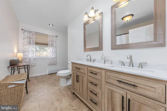 a spacious bathroom with a granite countertop sink a toilet and a mirror