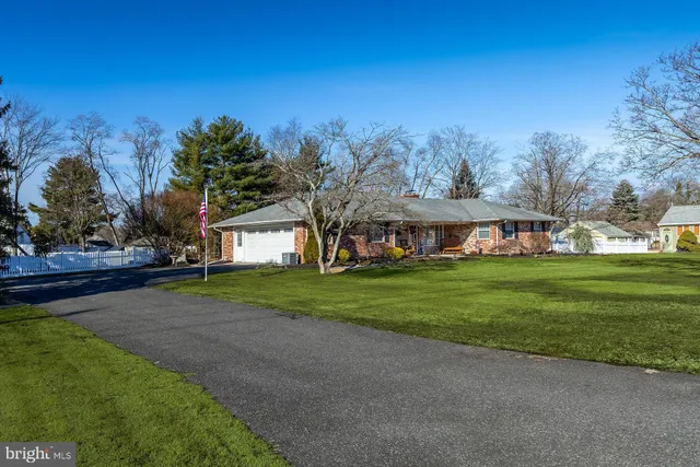 a view of a big house with a big yard and large trees