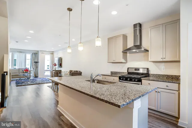 a kitchen with stainless steel appliances granite countertop a sink a stove and a wooden floors