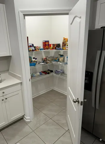 a view of storage and utility room with refrigerator and window