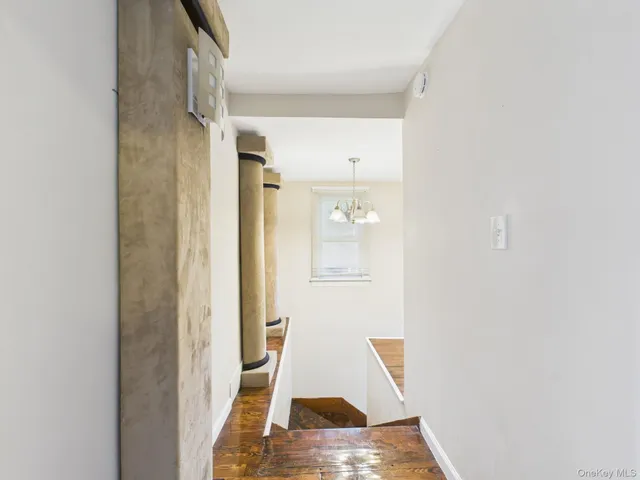 a view of a hallway with wooden floor and a bathroom