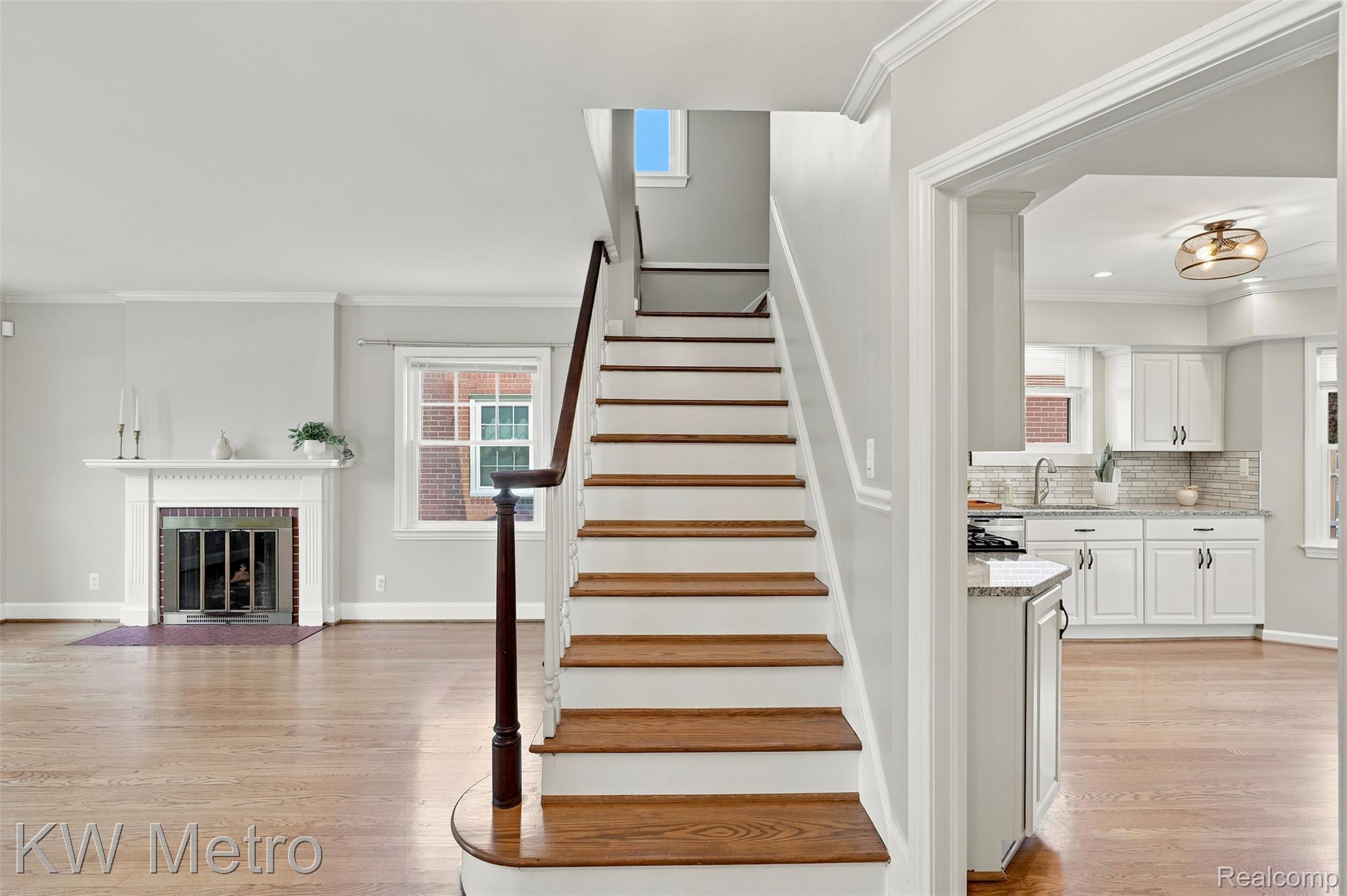 1458 Hampton Road Grosse Pointe, MI 48236 - Photo 7 of 43 Hardwood staircase with a rounded starter step and dark wood handrail, featuring light gray walls and crown molding