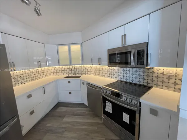 a kitchen with granite countertop a stove sink and microwave