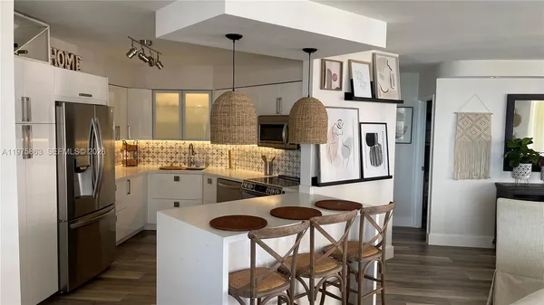 a kitchen with stainless steel appliances a refrigerator a stove a dining table and chairs with wooden floor
