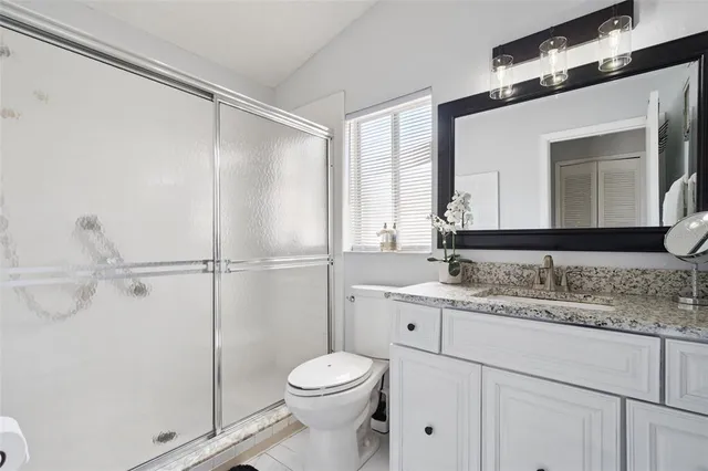 a bathroom with a granite countertop sink mirror vanity and toilet