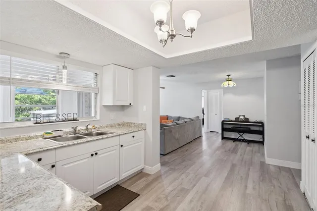 a open kitchen with stainless steel appliances kitchen island a stove a refrigerator a sink and white cabinets with wooden floor