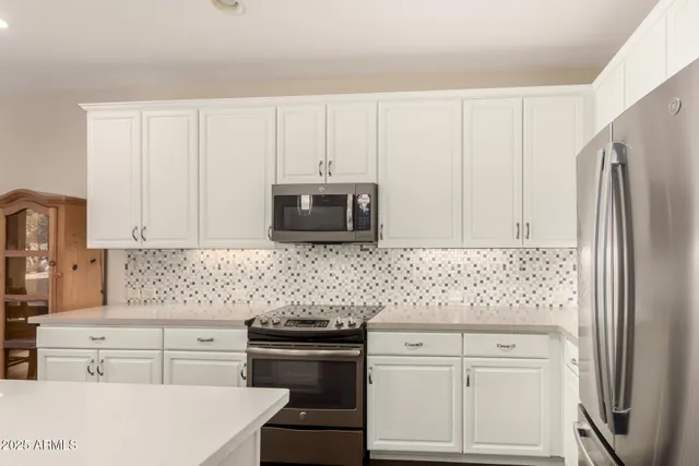 a kitchen with white cabinets and stainless steel appliances