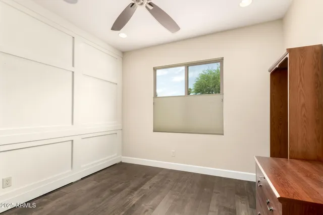 an empty room with wooden floor cabinet and windows