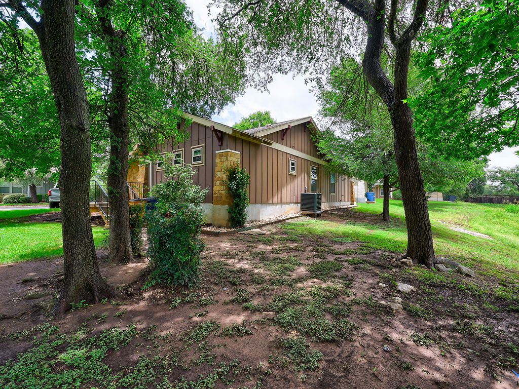 9707 Anderson Mill Road, Unit 22 Austin, TX 78750 - Photo 7 of 39 Mature trees shade this home's exterior, featuring board and batten siding with stone accents.