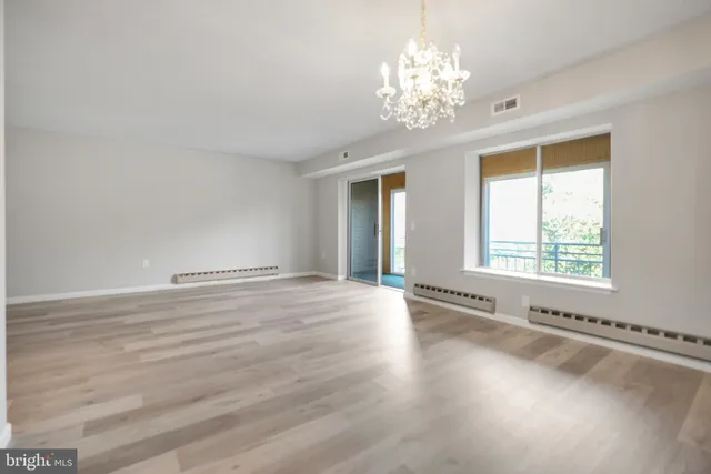 a view of an empty room with a window and wooden floor