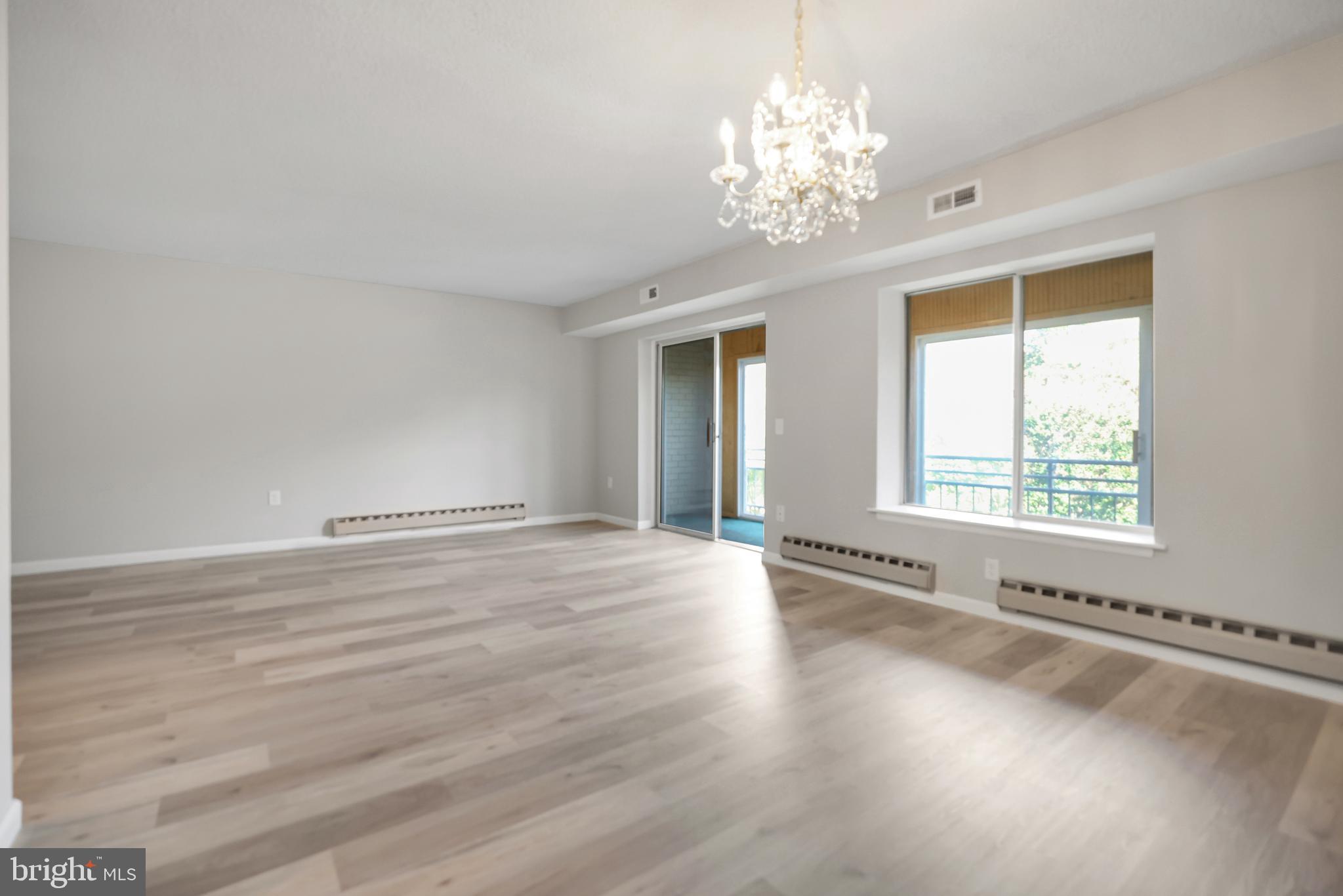 15121 Glade Drive, Unit 132F Silver Spring, MD 20906 - Photo 2 of 27 a view of an empty room with a window and wooden floor