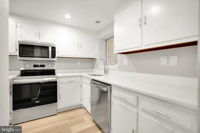 a kitchen with white cabinets stainless steel appliances and sink
