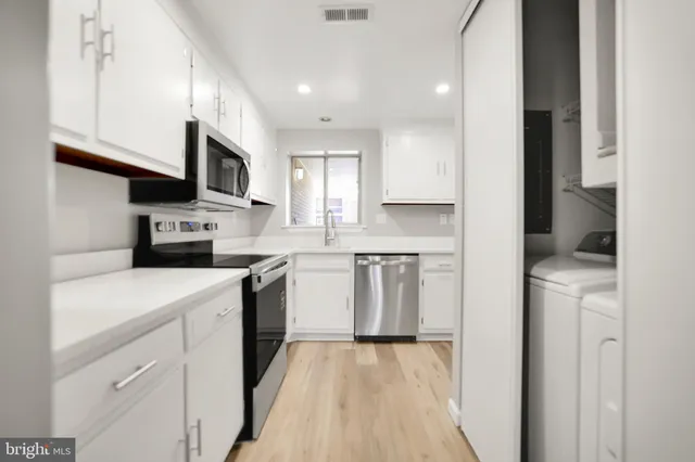 a kitchen with stainless steel appliances granite countertop a sink a stove a refrigerator and cabinets