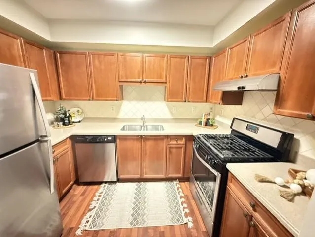 a kitchen with granite countertop a refrigerator stove top oven and sink