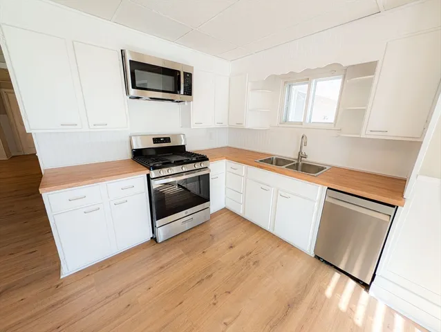 a kitchen with white cabinets appliances and wooden floor