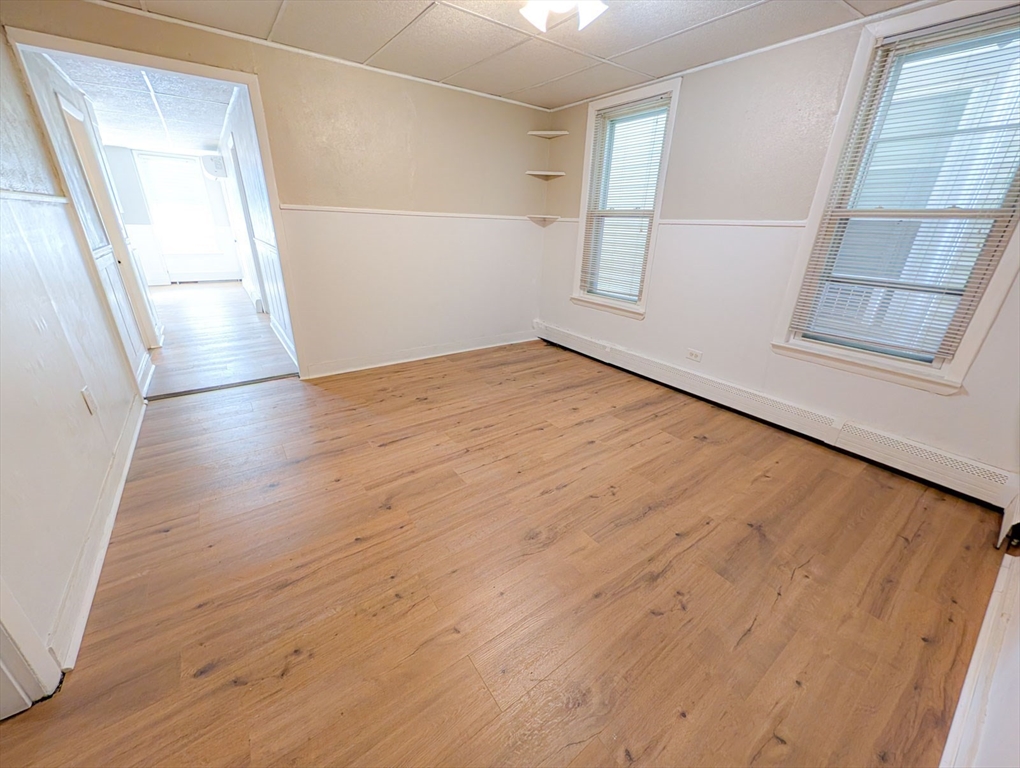 103-105 Homer Street, Unit 1 Boston, MA 02128 - Photo 6 of 17 an empty room with wooden floor and windows